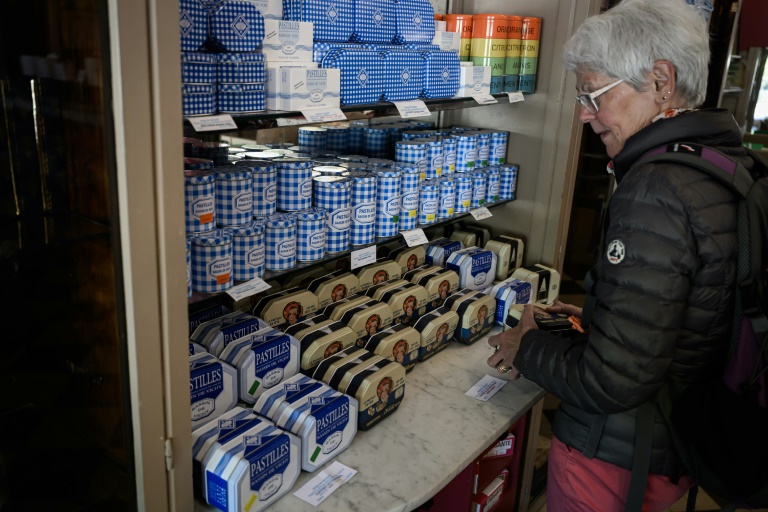Une cliente regarde les boîtes de pastilles à la menthe Vichy produits par la confiserie Maison Moinet dans une boutique à Vichy, le 13 mai 2025 dans l'Allier
