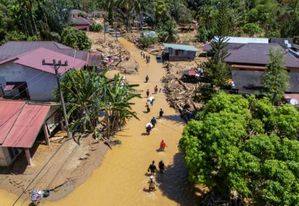 Cette photo aérienne montre des villageois pataugeant dans la coulée de boue pour trouver un abri après les crues soudaines du village de Tukka, dans le district de Tapanuli central, province de Sumatra du Nord, le 3 décembre 2025