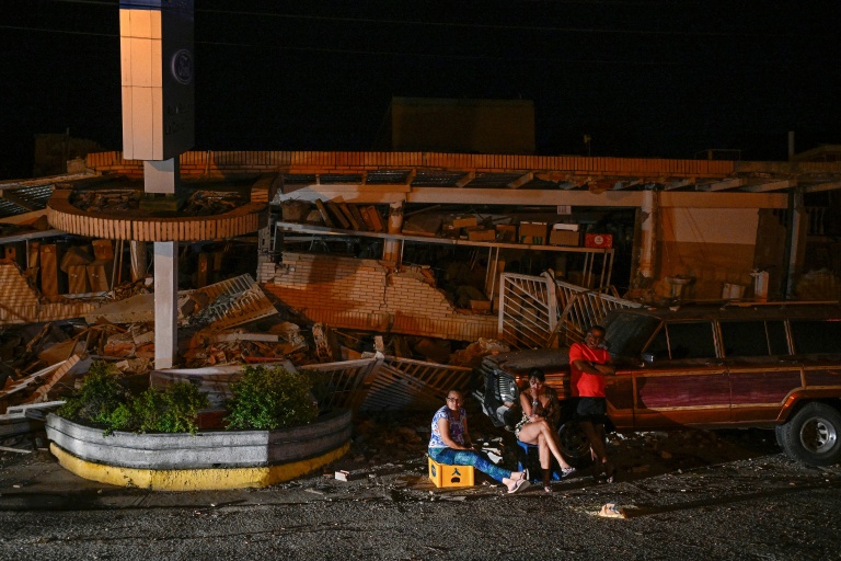Des habitants sont assis devant des immeubles effondrés après un séisme historique Catia La Mar, le 25 juin 2026. 