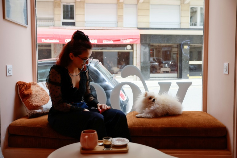 Sarah elGamal assise à côté de son chien poméranien Loulou au café pour chiens 
