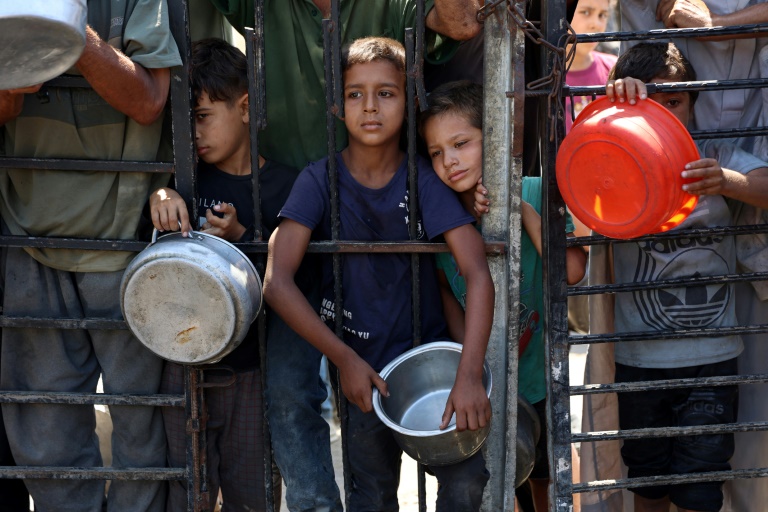 Des enfants palestiniens attendent de recevoir de la nourriture devant une organisation de charité locale distribuant du riz cuit, dans la ville de Gaza, le 23 août 2025