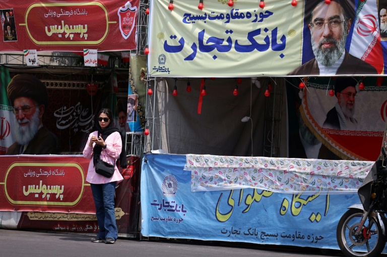 Une femme se tient sous une bannière représentant le guide suprême de l'Iran, l'ayatollah Mojtaba Khamenei, dans une rue de Téhéran, le 2 mai 2026