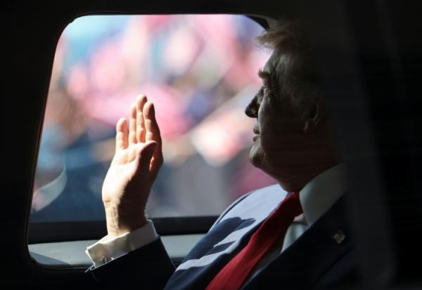 Le président américain Donald Trump effectue un salut de la main à bord de sa voiture, le 26 octobre 2025 à l'aéroport de Sepang en Malaisie