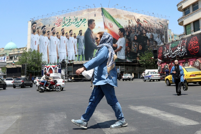 Une Iranienne passe devant un panneau montrant l'équipe de football de l'Iran, à Téhéran, le 18 mai 2026
