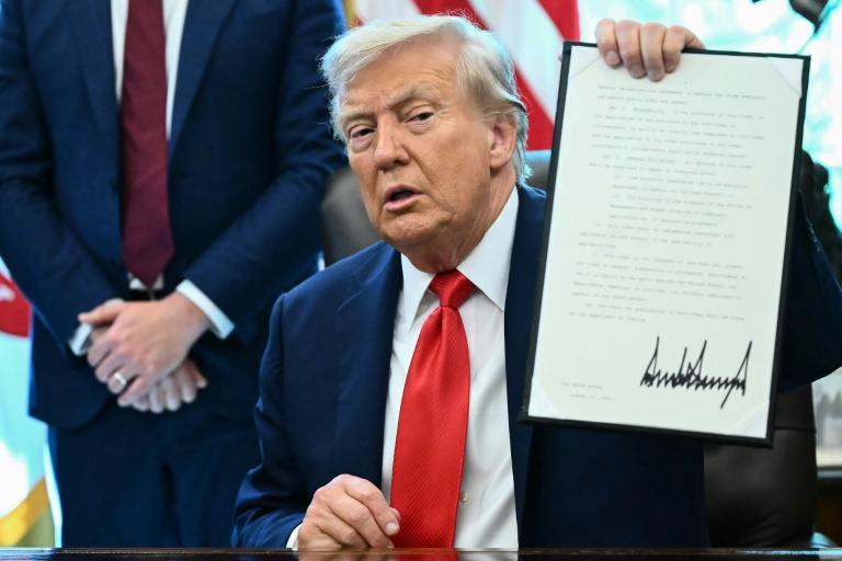 Le président américain Donald Trump montre un décret qu'il vient de signer dans le Bureau ovale à la Maison Blanche, le 25 août 2025 à Washington
