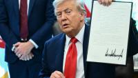 Le président américain Donald Trump montre un décret qu'il vient de signer dans le Bureau ovale à la Maison Blanche, le 25 août 2025 à Washington