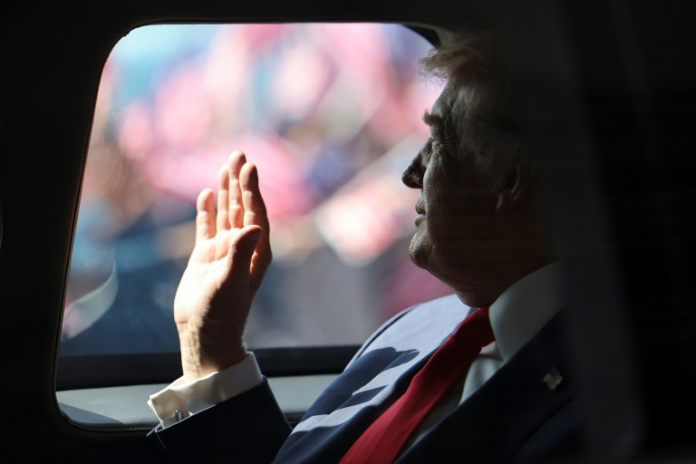 Le président américain Donald Trump effectue un salut de la main à bord de sa voiture, le 26 octobre 2025 à l'aéroport de Sepang en Malaisie