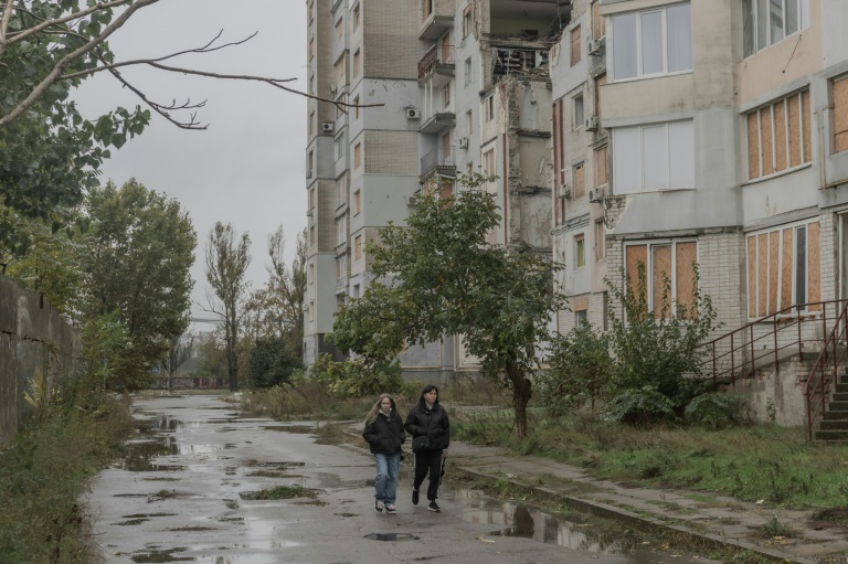 Des habitants marchent près d'un immeuble d'habitation endommagé par des attaques aériennes, le 30 octobre 2026 à Kherson, dans le sud de l'Ukraine 
