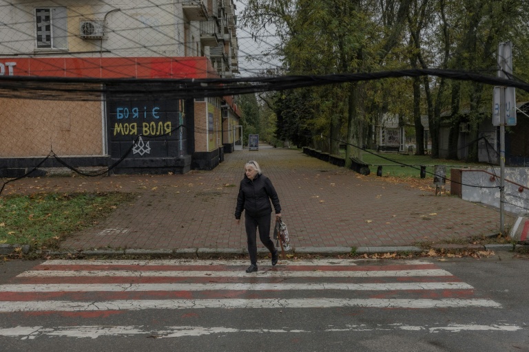 Une femme marche dans une une rue où des filets antidrones ont été disposés,  30 octobre 2026 à Kherson, dans le sud de l'Ukraine 
