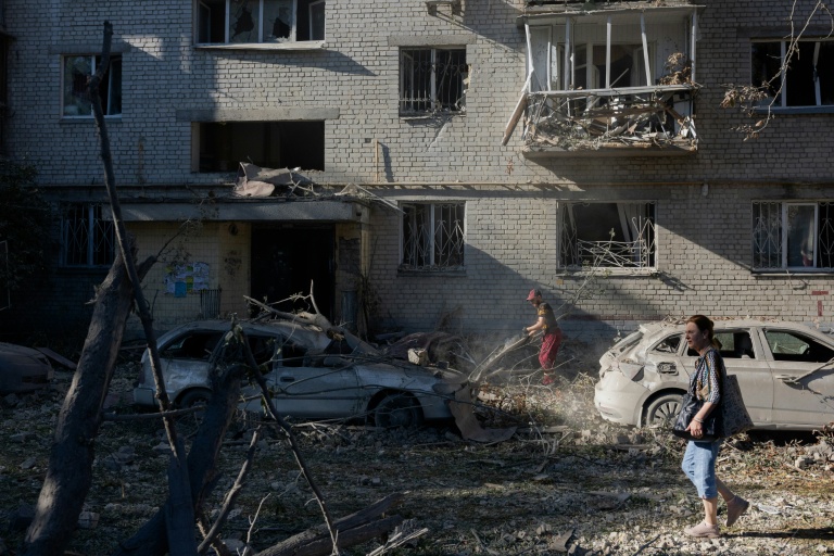 Une femme marche près d'un immeuble résidentiel endommagé à la suite d'une frappe à Kiev, le 20 août 2026