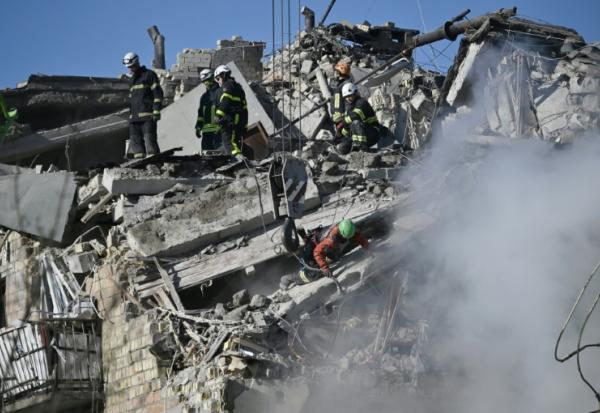 Des sauveteurs ukrainiens fouillent les décombres d'un immeuble résidentiel gravement endommagé lors d'une attaque massive de drones et de missiles russes sur Kiev, le 28 août 2025