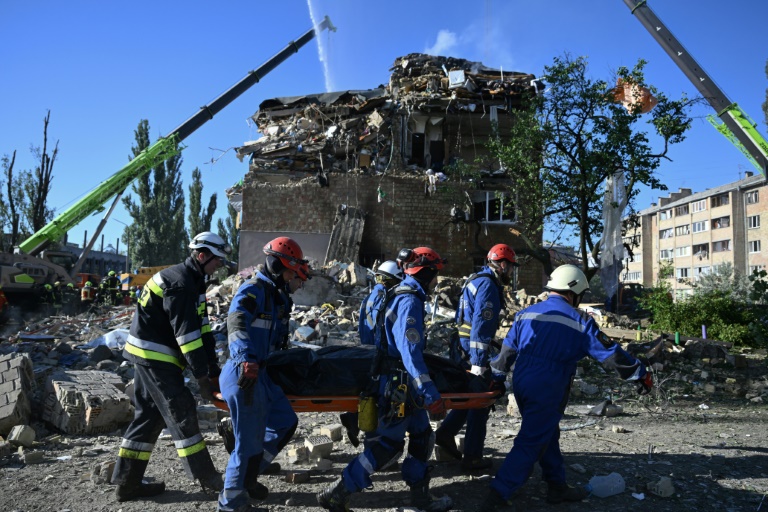 Des sauveteurs ukrainiens transportent le corps d'une victime près d'un immeuble résidentiel fortement endomagé lors d'une attaque massive de drones et de missiles russes sur Kiev, le 28 août 2025