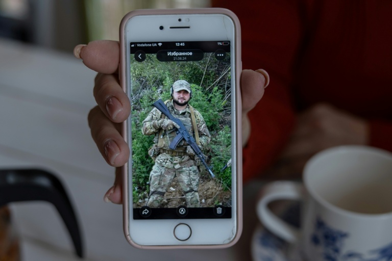 Nina, la mère du soldat ukrainien Iouriï Glodan tué au combat en septembre 2023 près de Bakhmout, montre une photo de son fils défunt, le 20 février 2026 à Odessa