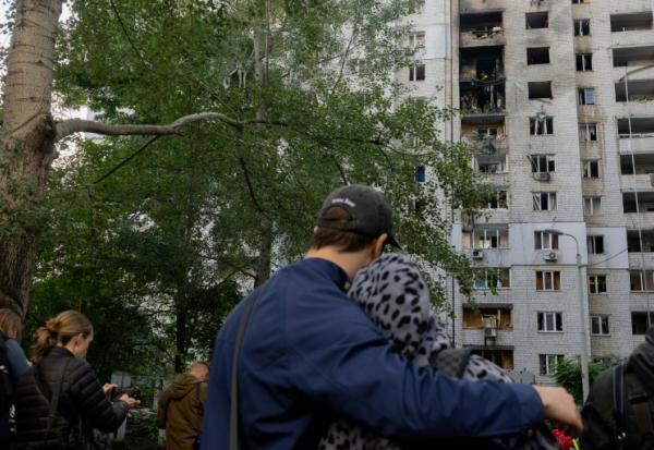 Des habitants observent un immeuble résidentiel endommagé après une frappe de drone russe à Kiev, le 25 septembre 2026