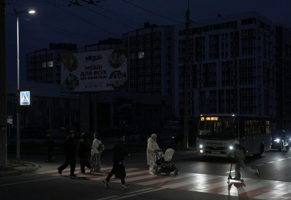 Des piétons traversent une rue sans éclairage à Tcherniguiv (Ukraine), le 22 octobre 2025, après une frappe russe contre une infrastructure énergétique de la région