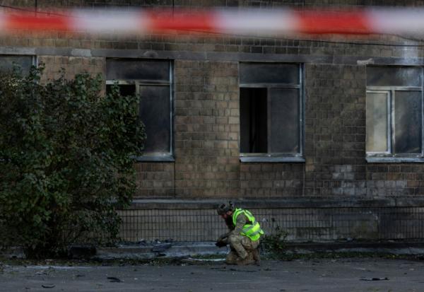 Un policier ukrainien inspecte des débris près d'un bâtiment endommagé par une frappe de drone russe à Kiev, le 1er octobre 2026