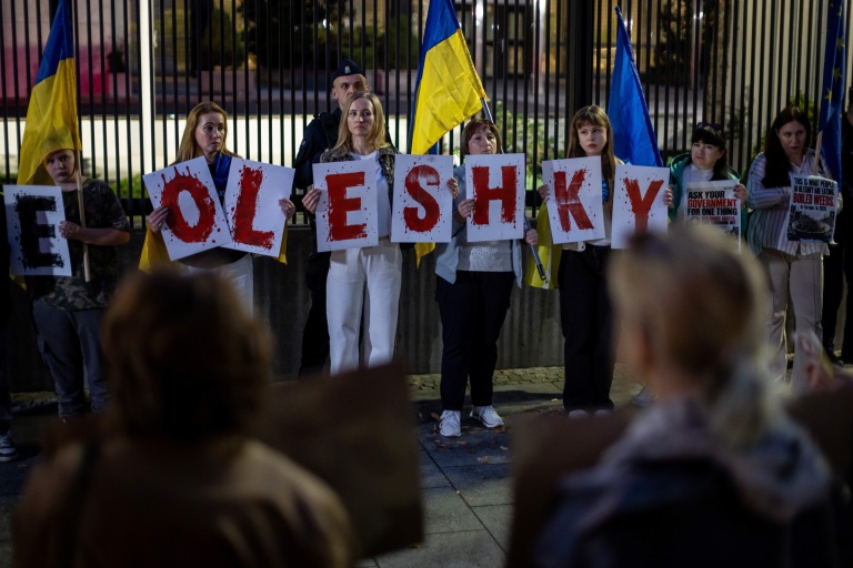 Des membres de la diaspora ukrainienne tiennent des pancartes formant le nom Oleshky (Olechky) devant l'ambassade américaine à Varsovie, le 6 octobre 2026, en Pologne