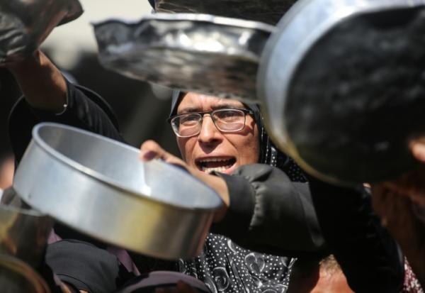 Nihaya Al-Masri (C), une Palestinienne déplacée lors d'une distribution alimentaire à Khan Younès, dans le sud du territoire palestinien, le 6 octobre 2026 

