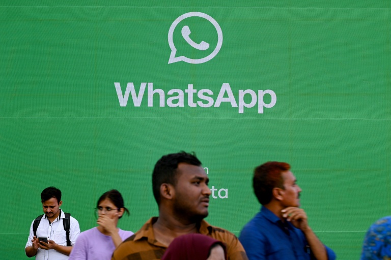 Des touristes devant une publicité pour l'application de messagerie Whatsapp, à Bombay le 25 août 2023