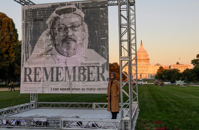 L'écrivaine turque Hatice Cengiz (d), fiancée du journaliste et dissident saoudien Jamal Khashoggi, devant un portrait du journaliste Jamal Khashoggi assassiné, après son dévoilement sur le National Mall à Washington, le 1er octobre 2021