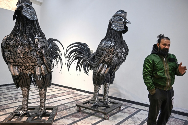 Le sculpteur Ehtisham Jadoon à côté de sculptures de coqs fabriquées à partir de ferraille, dans son atelier situé à la périphérie d'Islamabad, le 29 décembre 2025 au Pakistan
