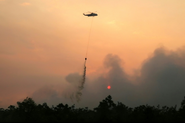 Un hélicoptère largue de l'eau sur des forêts et des terres en feu dans la région de Petuk Katimpun, à Palangkaraya, dans la province du Kalimantan central, en Indonésie, le 13 août 2026

A helicopter drops water on burning forests and land in the Petuk Katimpun area, Palangkaraya, in Indonesia's Central Kalimantan province, on August 13, 2026.