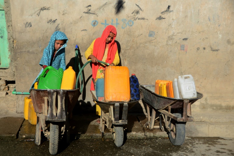 Des jeunes filles remplissent des jerrycans avec de l'eau potable à Kandahar, le 24 mai 2022 en Afghanistan