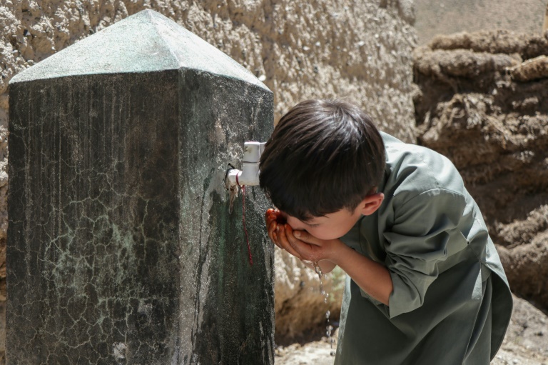 Un enfant boit de l'eau au robinet d'une fontaine à Qavariyak, dans la province de Bamiyan, le 18 juin 2025 en Afghanistan