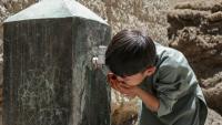 Un enfant boit de l'eau au robinet d'une fontaine à Qavariyak, dans la province de Bamiyan, le 18 juin 2025 en Afghanistan