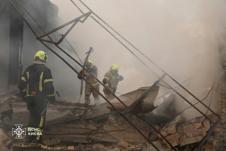 Photo diffusée par le Service d'État ukrainien pour les situations d'urgence, le 11 juillet 2026, montrant des pompiers luttant contre un incendie dans un entrepôt endommagé par une frappe de missiles russes à Kiev, en Ukraine