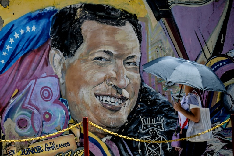 Une femme se protégeant du soleil avec un parapluie arrive au mausolée de l'ancien président vénézuélien Hugo Chavez à Caracas, le 5 mars 2026