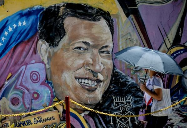 Une femme se protégeant du soleil avec un parapluie arrive au mausolée de l'ancien président vénézuélien Hugo Chavez à Caracas, le 5 mars 2026