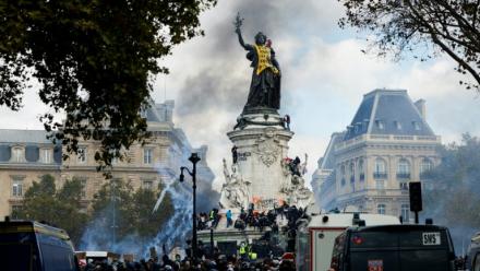 De la fumée enveloppe la Statue de la République, recouverte d'une banderole jaune, lors d'une manifestation contre la vie chère, place de la République à Paris, le 17 octobre 2026