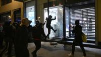 Des personnes s'attaquent à la vitrine d'un magasin à Paris le 18 octobre 2026, au lendemain d'une journée de manifestations marquée par des violences