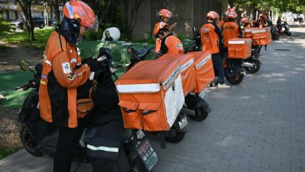 Des livreurs de repas attendent des commandes au bord d'une rue à Pékin, le 2 septembre 2026