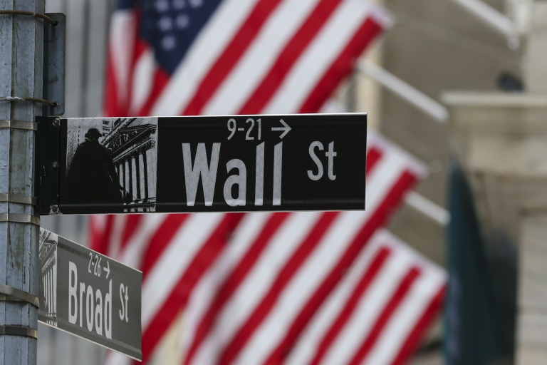 Le drapeau américain flotte derrière le panneau indiquant Wall Street, la rue qui abrite la Bourse de New York, le 22 avril 2026