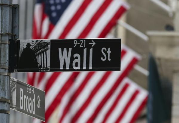 Le drapeau américain flotte derrière le panneau indiquant Wall Street, la rue qui abrite la Bourse de New York, le 22 avril 2026