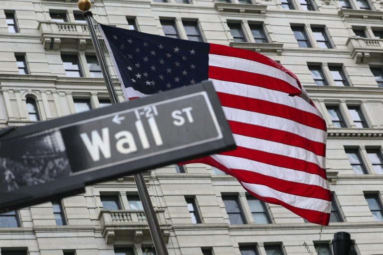 Le drapeau américain flotte derrière un panneau de Wall Street à New York le 22 avril 2026