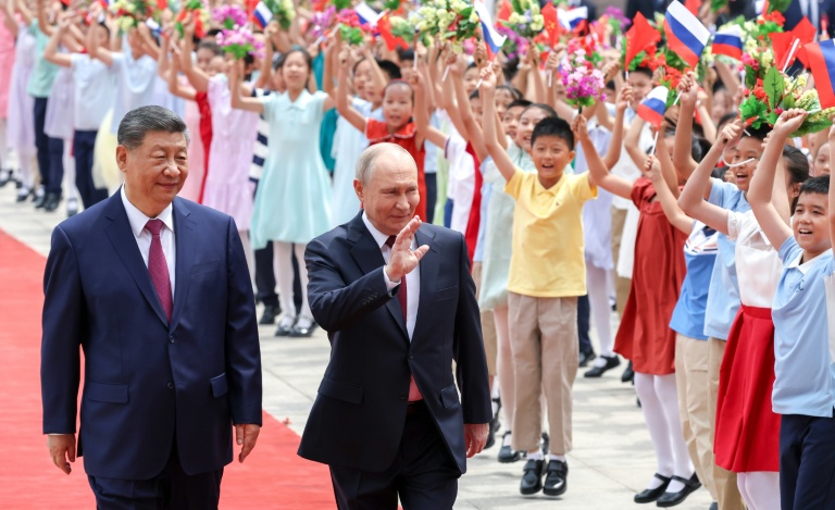 Photo diffusée par l'agence de presse russe Sputnik montrant le président russe Vladimir Poutine (g) et le président chinois Xi Jinping se serrant la main lors d'une cérémonie de signature à Pékin, le 20 mai 2026