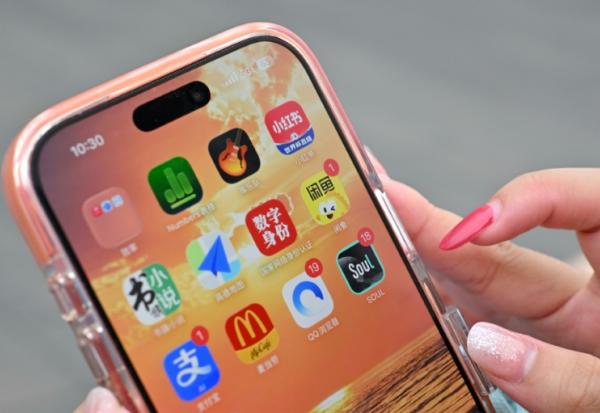 Une utilisatrice de Xiaohongshu se préparant à ouvrir l'application (en haut à droite de son écran) alors qu'elle visite la Cité interdite à Pékin, le 11 juillet 2026