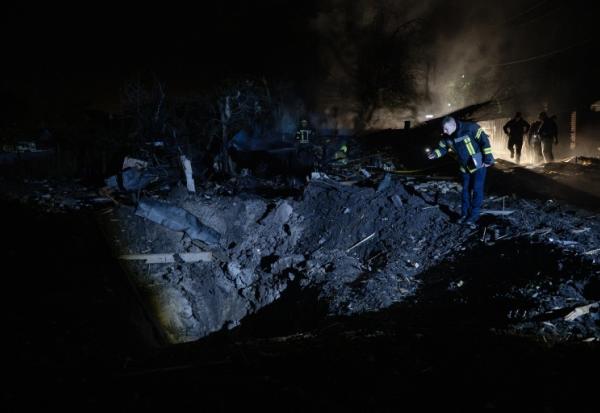Un pompier ukrainien examine un cratère après une frappe de missile russe qui a touché des habitations à Kiev dans la soirée du 21 octobre 2026